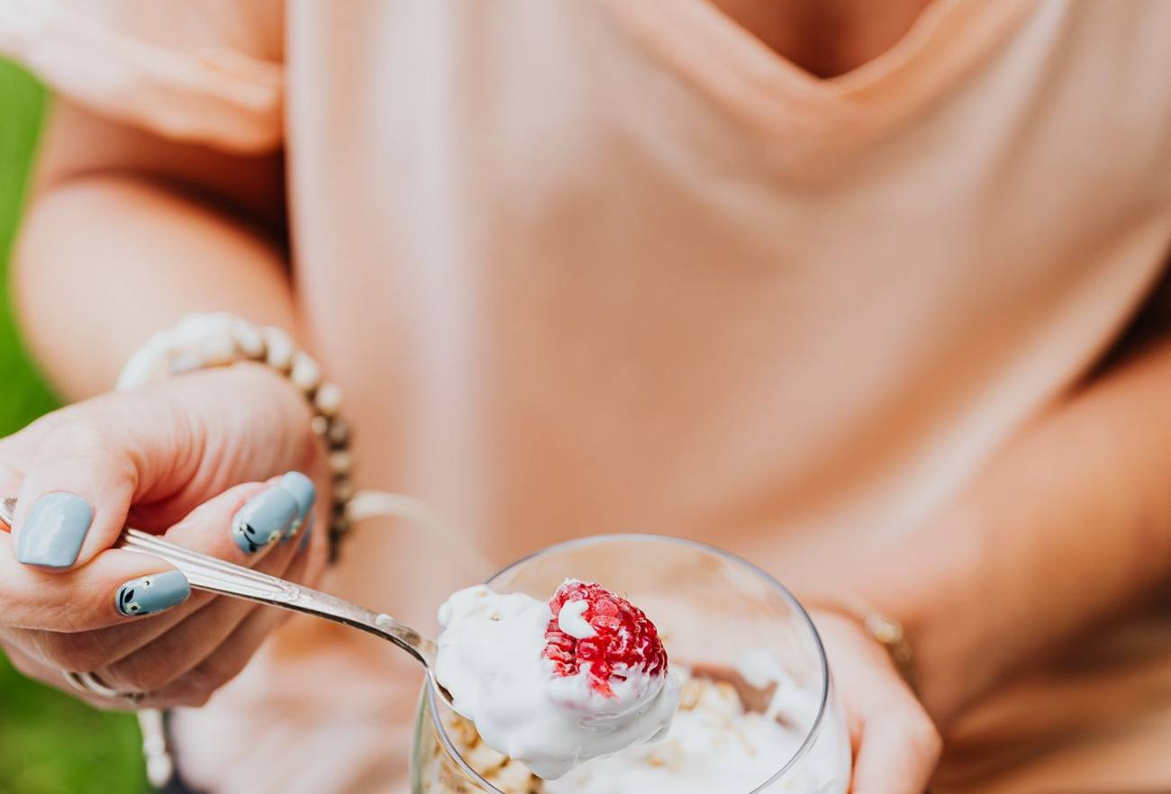 Femme qui savoure un bol de yaourt, granola et fruits frais